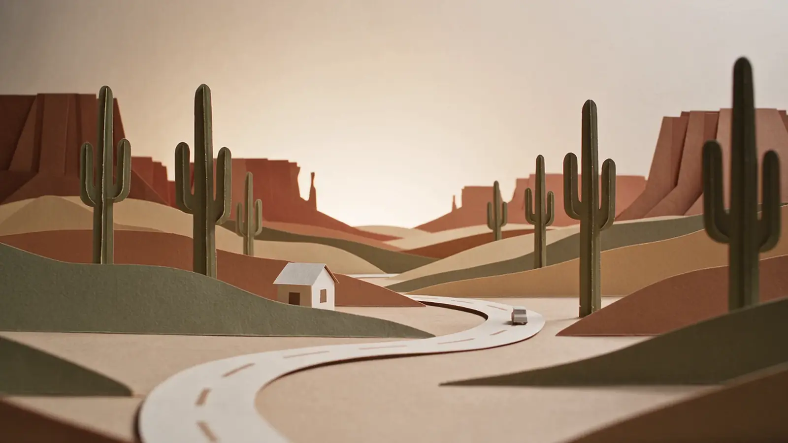 A cut-paper Arizona desert with a small house and a car on a winding road
